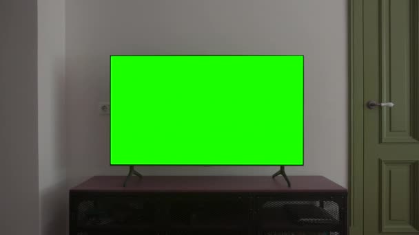 Телевизионный макет. Экран LSD Smart TV с бланкетным зеленым фоном в гостиной перед просмотром фильмов и видео в Интернете в 4К — стоковое видео