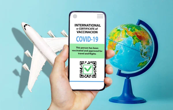 Coronavirus vaccination certificate or vaccine passport for travellers concept. COVID-19 immunity e-passport in the smartphone mobile app for international travelling with model plane and globe.