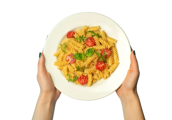 Pasta voedsel op een witte geïsoleerde achtergrond met vrouwelijke handen. Italiaanse fusilli pasta met tomaten en basilicum op een witte plaat. — Stockfoto