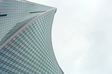 Gökdelenlerin modern mimarisi, ofis binaları ve alışılmadık geometriye sahip iş merkezleri. Şehrin iş bölgesinde gri gökyüzüne karşı modern gökdelen