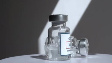 Coronavirus covid aşıları bir tıp laboratuarında beyaz arka planda döner. Aşı, koronavirüs salgınından korunma.