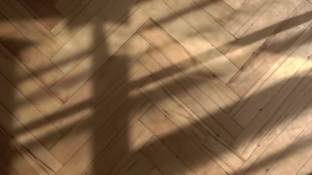 나무로 된 바닥에 창문 배경의 그림자가 있다. 아침 햇살이 비치는 고전적 인 역 룸의 나무 파켓 바닥. 커튼의 그림자를 움직이는 빈 빈티지 오래 된 내부 — 비디오