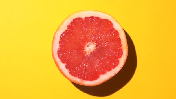 Grapefruit orange rotating with a cocktail umbrella in the sunlight on a colored blue background. Fruit juices, relaxation, tropics and relaxation concept. — Stock Video