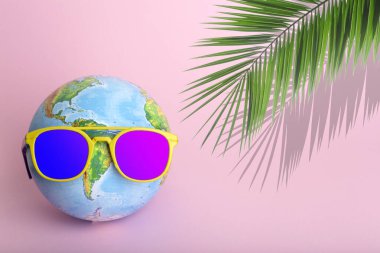 Seyahat yaz konsepti. Renkli arka planda güneş gözlüğü takan bir dünya. Güneş, tatil ve turizm yaratıcı fikir.