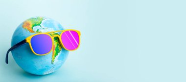 Seyahat yaz konsepti. Renkli arka planda güneş gözlüğü takan bir dünya. Güneş, tatil ve turizm yaratıcı fikir.