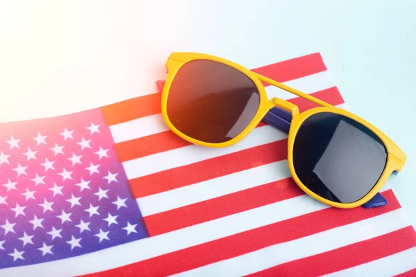 Gafas de sol de verano en la bandera de Estados Unidos y fondo de color. Vacaciones, verano, sol y concepto de vacaciones en los Estados Unidos. — Foto de Stock