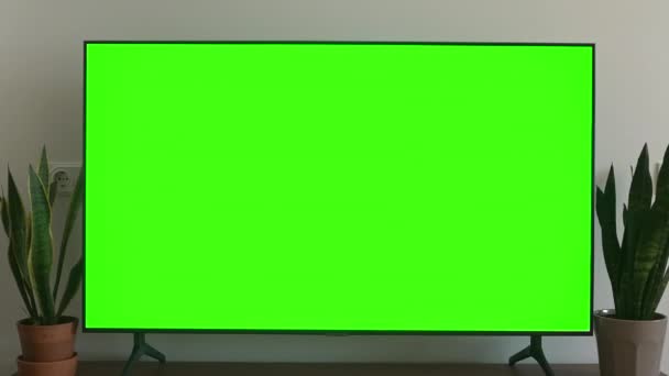 Ekran telewizyjny. Ekran LSD smart TV z zielonym tłem w salonie przed oglądaniem filmów i filmów w Internecie w rozdzielczości 4K — Wideo stockowe