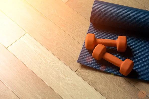 Yoga e fitness sfondo. Pavimento in parquet o laminato con tappeto e manubri per l'allenamento in una sala yoga o in palestra — Foto Stock