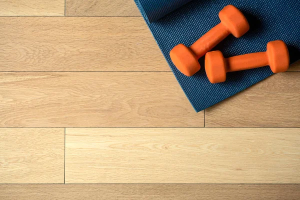 Yoga e fitness sfondo. Pavimento in parquet o laminato con tappeto e manubri per l'allenamento in una sala yoga o in palestra — Foto Stock