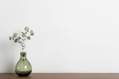 Masa arkasını boşalt. İçinde vazo ve bitki olan ahşap masa bir evin ya da ofisin oturma odasındaki beyaz duvara karşı. Boş minimal İskandinav iç tasarım arka planı.