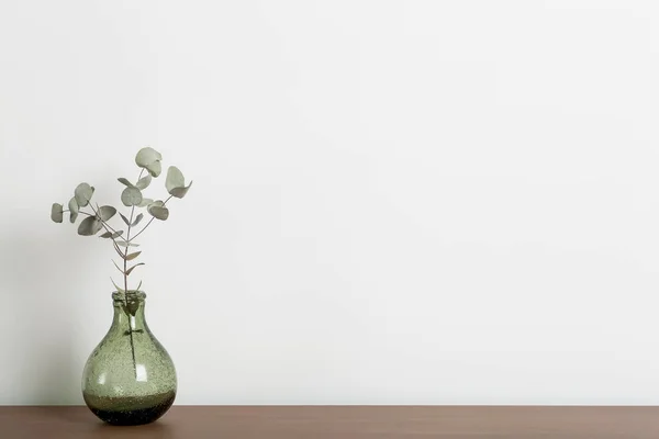 Masa arkasını boşalt. İçinde vazo ve bitki olan ahşap masa bir evin ya da ofisin oturma odasındaki beyaz duvara karşı. Boş minimal İskandinav iç tasarım arka planı.
