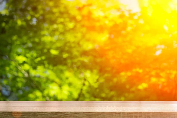 Sfondo tavolo in legno nella foresta. Sfondo di una foresta verde sfocata estiva con luce solare — Foto Stock