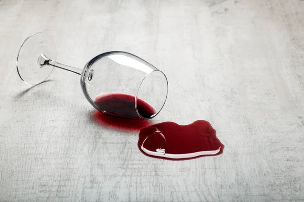 Suelo de madera con vaso volcado de vino tinto. Vino derramado en un suelo de parquet laminado de madera con protección contra la humedad. —  Fotos de Stock