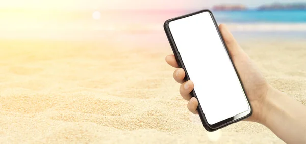 Empty screen smartphone in hand on the of a summer sunny background. Beach, sea, rest, vacation banner background and empty screen phone.