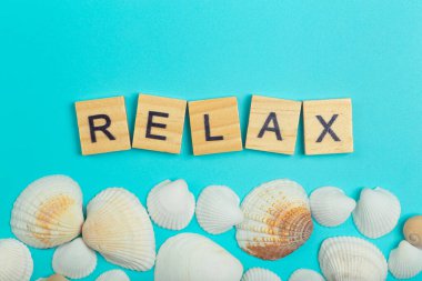 Rahat ol. Yazı, deniz kabuklarıyla açık mavi arka planda rahatla.