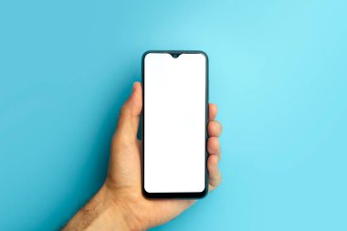 Elinde renkli mavi afiş olan boş bir akıllı telefon. Asgari arkaplan üzerinde boş ekran olan model telefon