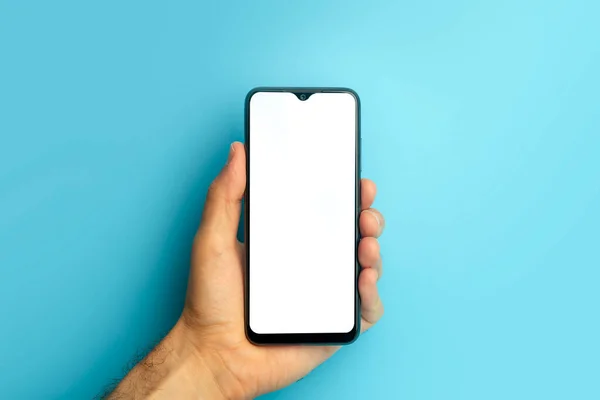 Empty smartphone in hand on colored blue banner background. Mockup phone with blank screen on minimal background — Stock Photo, Image