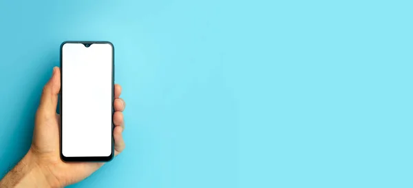 Empty smartphone in hand on colored blue banner background. Mockup phone with blank screen on minimal background — Stock Photo, Image