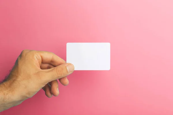 Empty plastic card in hand on colored background. ID or credit money card isolate