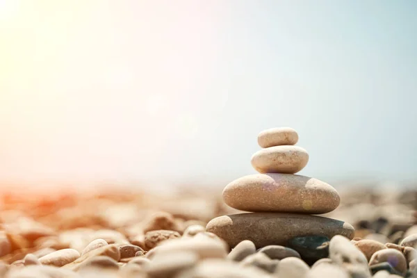 Zen-Steine sind der Hintergrund. Eine Pyramide aus Kieselsteinen vor dem Hintergrund von Himmel, Meer und Strand. Meditation, Yoga, Beruhigung des Geistes und Entspannungskonzept. — Stockfoto