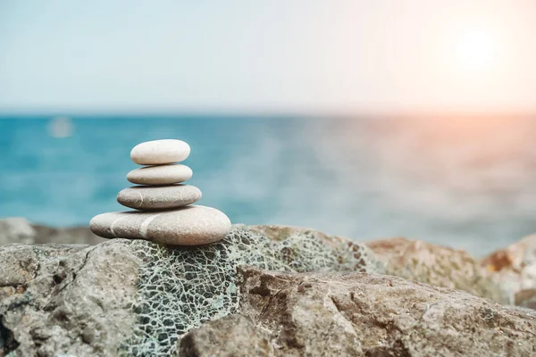 Zen-Steine sind der Hintergrund. Eine Pyramide aus Kieselsteinen vor dem Hintergrund von Himmel, Meer und Strand. Meditation, Yoga, Beruhigung des Geistes und Entspannungskonzept. — Stockfoto