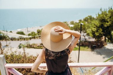 Şapkalı kız yazın Antalya 'nın Türk deniz manzarasına bakıyor. Türkiye 'de seyahat, tatil, keyif konsepti.
