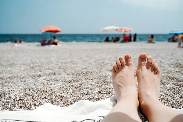 Bain de soleil et fille relaxante sur la plage de la mer. Pieds et jambes féminins sur la plage sous le soleil. Loisirs, détente, vacances et concept d'été. — Photo