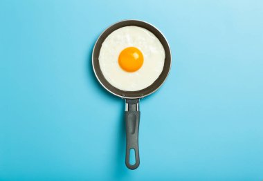 Yağda yumurta asgari düzeyde. Boş mavi bir arka planda kızartma tavasında kızarmış yumurta. Yaratıcı kahvaltı ve yemek fikri.