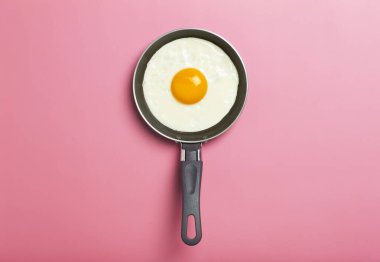 Yağda yumurta asgari düzeyde. Boş pembe bir arka planda kızartma tavasında kızarmış yumurta. Yaratıcı kahvaltı ve yemek fikri.