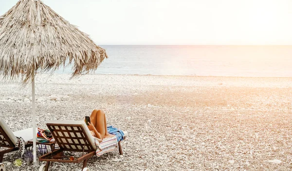 해변에서 여자가 햇볕 라운지에서 쉬고 있어. 해변의 햇살 아래서 휴식 과 휴식. — 스톡 사진