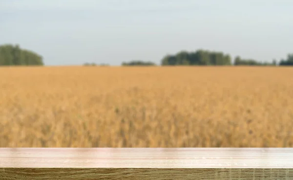 Fondo tavola di grano. Tavolo di legno vuoto sullo sfondo di un campo estivo di grano dorato o segale. Modello per alimenti a base di farina, cottura, pane, concetto di birra. — Foto Stock