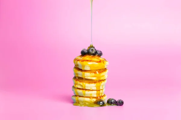 Panqueques con bayas sobre un fondo de bandera rosa. Deliciosos panqueques exuberantes con arándanos y jarabe para el almuerzo sobre un fondo de color mínimo. Hermosa comida brillante foto — Foto de Stock