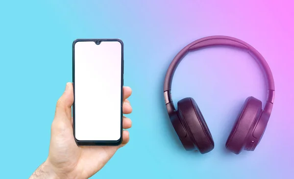 Ακουστικά με smartphone mock up. Ακουστικά ήχου σε έγχρωμο νέον φόντο με μια κενή οθόνη smartphone. Μουσική εφαρμογή, ακούγοντας podcast και ηχητικά βιβλία. — Φωτογραφία Αρχείου