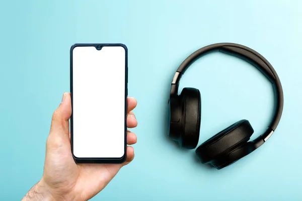 Headphones with smartphone mock up. Sound audio headphones on a colored neon background with a blank smartphone screen. Music app, listening to podcasts and audiobooks concept. — Stock Photo, Image