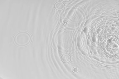 Su sakince dalgalanan arka plan. Sıvı beyaz bir yüzeyde su dokusu, daireler ve kabarcıklar. Kozmetik ürünler ve düz tasarım konsepti