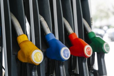 Petrol fiyatlarının yüksek olduğu bir dönemde modern bir benzin istasyonunda asılı duran yakıt pompası başlıkları. Küresel enerji krizini gösteren kavramsal bir fotoğrafçılık, benzin maliyetlerini artırıyor. Yüksek kalite fotoğraf