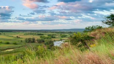 Nehiri olan güzel bir vadi, büyük bulutları ve parlak güneşi olan mavi bir gökyüzü. Hava 4K UHD