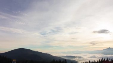 Dağlarda romantik renkli gündoğumu. Güneş doğar, mavi ve turuncu bulutlar gökyüzünde akar. Muhteşem muhteşem bir manzara. Yavaş çekim süresi 4K görüntüsü.