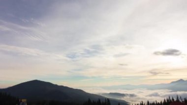 Dağlarda romantik renkli gündoğumu. Güneş doğar, mavi ve turuncu bulutlar gökyüzünde akar. Muhteşem muhteşem bir manzara. Yavaş çekim süresi 4K görüntüsü.