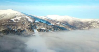 Dağlarda görkemli bir gündoğumu görüntüsü. Dağlar arasındaki vadi sisle kaplıdır ve yükselen güneşin sıcak ışınlarıyla aydınlanır. Dağlar doğal ormanlarla kaplı..