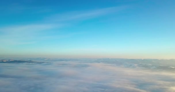 Foto aérea de majestuoso amanecer en las montañas. Valle entre las montañas está cubierto de niebla y está iluminado por los cálidos rayos del sol naciente. Montañas cubiertas de bosque natural. — Vídeos de Stock