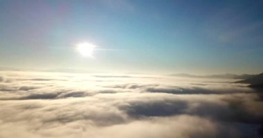 Dağlarda görkemli bir gündoğumu görüntüsü. Dağlar arasındaki vadi sisle kaplıdır ve yükselen güneşin sıcak ışınlarıyla aydınlanır. Dağlar doğal ormanlarla kaplı..