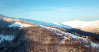 Dağlarda görkemli bir gündoğumu görüntüsü. Dağlar arasındaki vadi sisle kaplıdır ve yükselen güneşin sıcak ışınlarıyla aydınlanır. Dağlar doğal ormanlarla kaplı..
