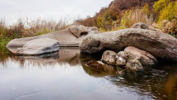 Höstträd och stora stenblock runt omkring. En vattenkaskad på hösten bäck med fallna blad. Vatten rinner runt stenarna i ån. Aktovsky Canyon, Ukraina. — Stockvideo