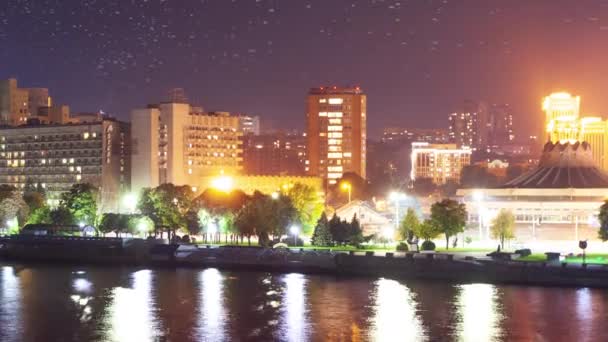 Paisaje urbano abstracto con edificios modernos de gran altura rascacielos y luces de la ciudad reflejadas en la superficie del espejo de agua del tranquilo río o lago en la noche oscura. Sin gente, timelapse. — Vídeo de stock