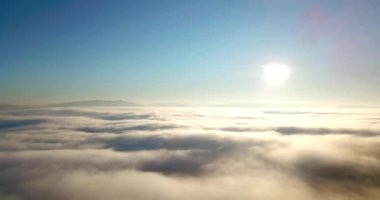 Dağlarda görkemli bir gündoğumu görüntüsü. Dağlar arasındaki vadi sisle kaplıdır ve yükselen güneşin sıcak ışınlarıyla aydınlanır. Dağlar doğal ormanlarla kaplı..