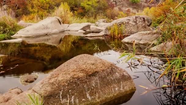 Осінні дерева і великі кам'яні валуни навколо. Водопровідний каскад в осінній струмці з поваленим листям. Вода тече навколо каменів у річці. Каньйон Актовський, Україна.. — стокове відео