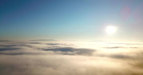 Foto aérea de majestuoso amanecer en las montañas. Valle entre las montañas está cubierto de niebla y está iluminado por los cálidos rayos del sol naciente. Montañas cubiertas de bosque natural. — Vídeos de Stock