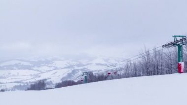 Kar kaplı dağların arka planında kayak kaldırımları ve bir dağ buzulu. Sandalyeler asansörde bir aşağı bir yukarı hareket ediyor. Hafta sonu turizm için kayakçılar, snowboardcular ve turistler geldi.