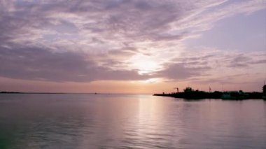 Sunset timelapse and boat silhouette at Olhão, capital of Ria Formosa wetlands natural conservation region landscape, Algarve, southern Portugal.
